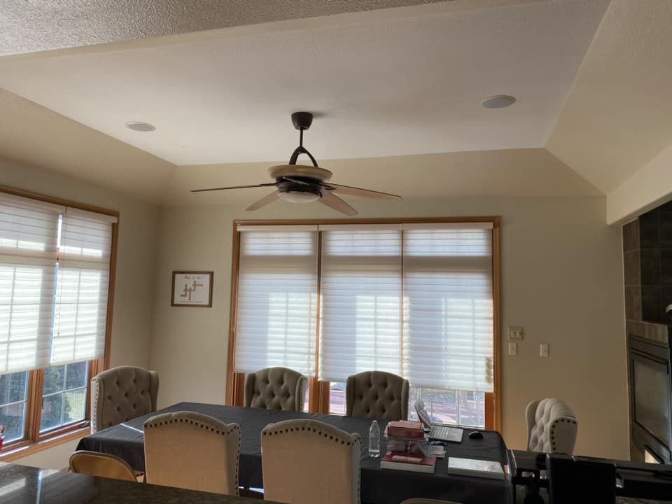 Existing dining room before renovation with ceiling fan, large windows with roller shades, and tray ceiling